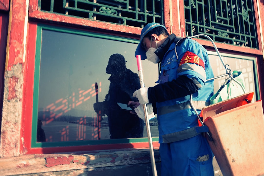 worker-in-blue-uniform-cleans-window-with-spray-bottle-fyjqgxd5v1g